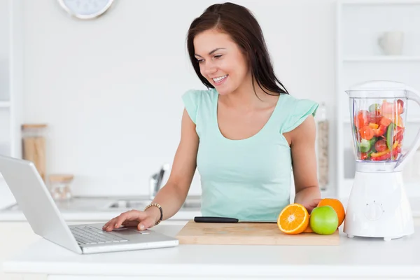 Jovem morena com um laptop e frutas — Fotografia de Stock