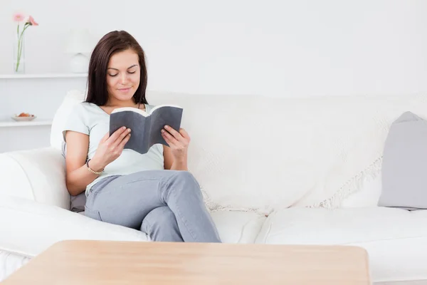 Usmívající se černovlasá žena čte knihu — Stock fotografie