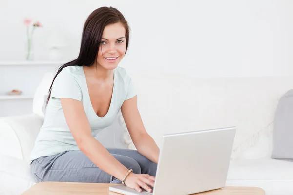 Onu laptop yazarak gülümseyen genç kadın — Stok fotoğraf