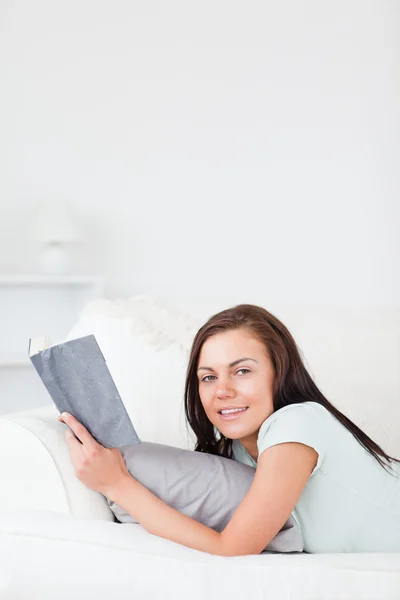 Charming woman on a sofa with a book — Stock Photo, Image