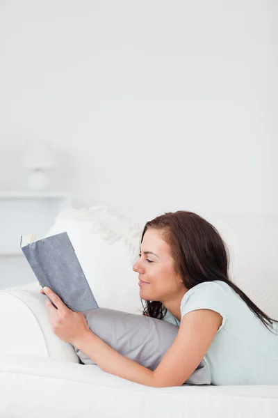 Okouzlující žena na pohovce, čtení knihy — Stockfoto