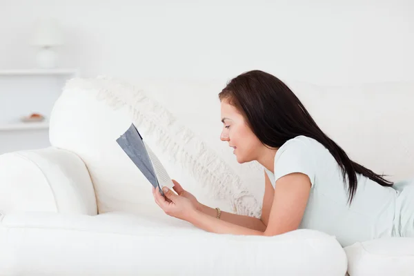 Mujer relajada en un sofá leyendo un libro — Foto de Stock