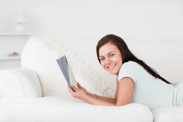 Mujer relajada en un sofá sosteniendo un libro —  Fotos de Stock