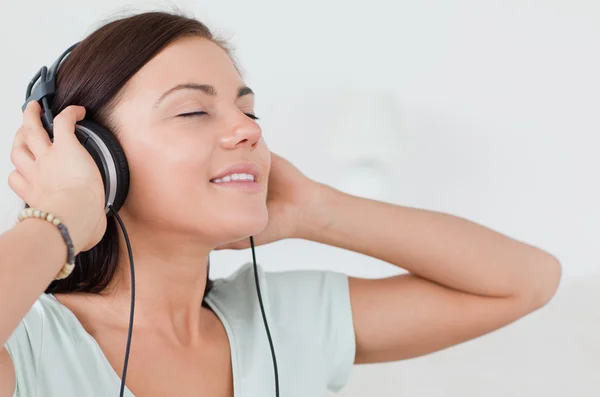 Gros plan d'une charmante brune écoutant de la musique — Photo
