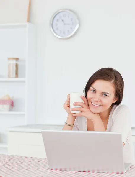 Portrait d'une brune utilisant son ordinateur portable et prenant un thé — Photo