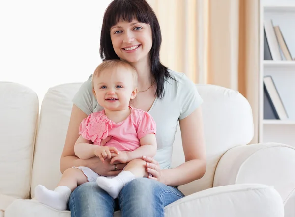 Hermosa mujer sosteniendo a su bebé en sus brazos mientras está sentada en un —  Fotos de Stock