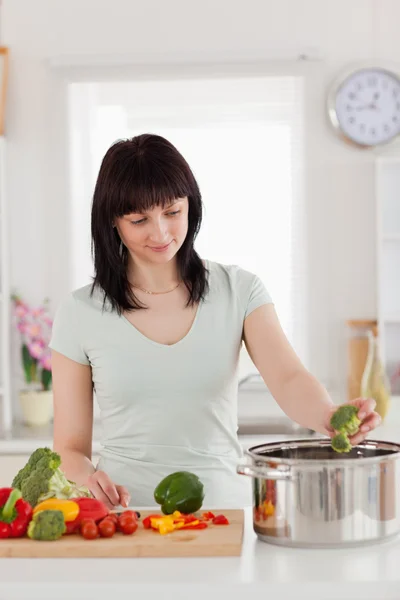Beautiful brunette woman cooking vegetables — Stock Photo, Image