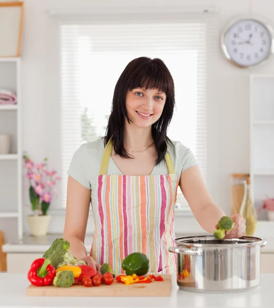 Mooie brunette vrouw die zich voordeed tijdens het koken van groenten — Stockfoto