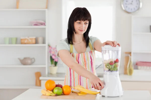 Lovely brunette woman using a mixer while standing — Stock Photo, Image