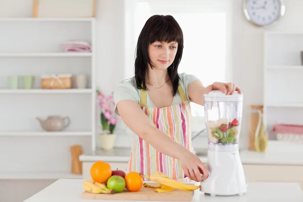 Linda mulher morena usando um mixer enquanto está de pé — Fotografia de Stock