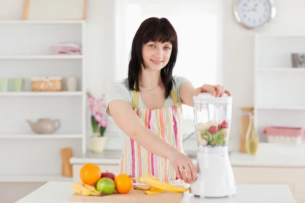 Attractive brunette woman using a mixer while standing — Stock Photo, Image