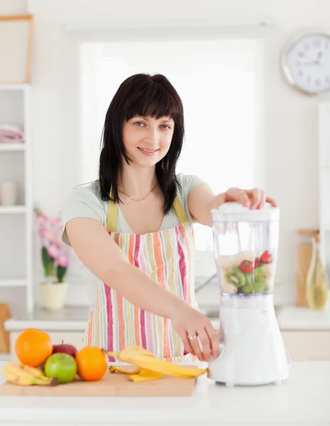 Beautiful brunette woman using a mixer while standing — Stock Photo, Image