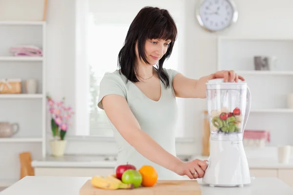 Cute brunette woman using a mixer while standing — Stock Photo, Image