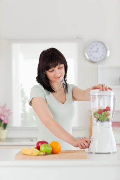 Cute brunette female using a mixer while standing — Stock Photo, Image