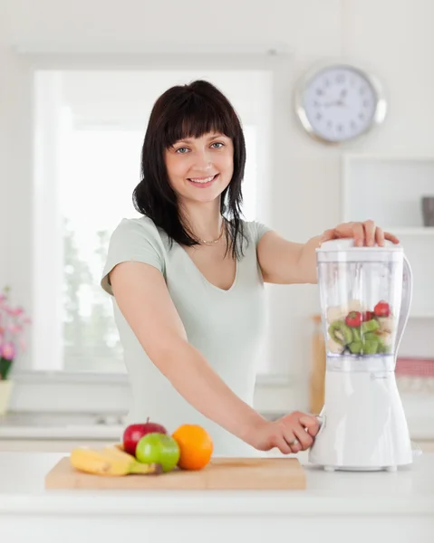 Good looking brunette female using a mixer while standing — Stock Photo, Image