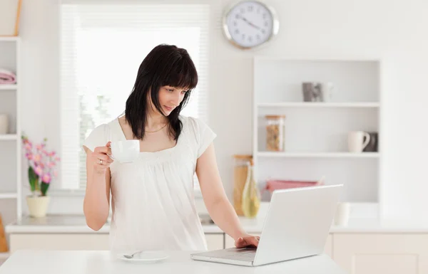 Gut aussehende brünette Frau hält eine Tasse Kaffee, während sie entspannt — Stockfoto