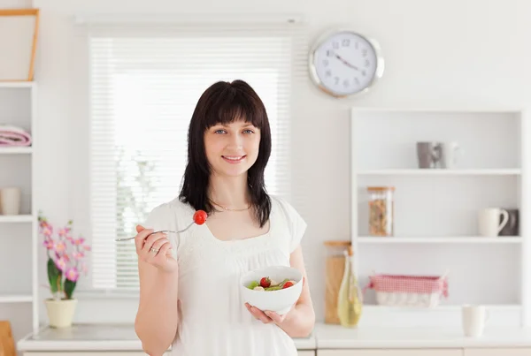 Dobry patrząc brunetka kobieta jedzenie pomidor podczas holdin — Zdjęcie stockowe