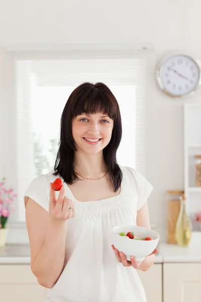 Bonita morena hembra comiendo un tomate cherry mientras sostiene un bo — Foto de Stock