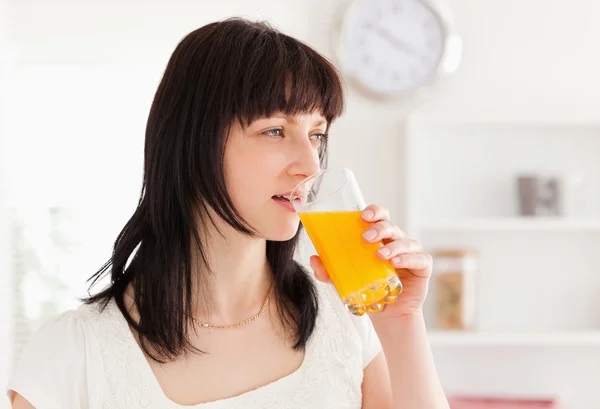 Belle brune buvant un verre de jus d'orange tandis que sta — Photo