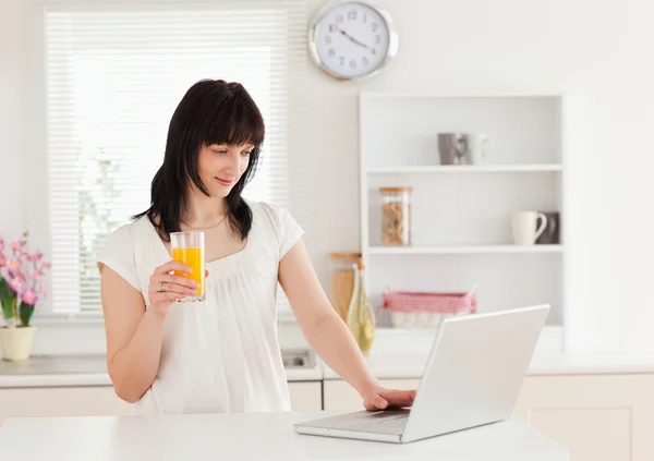 Schöne brünette Frau hält ein Glas Orangensaft, während r — Stockfoto