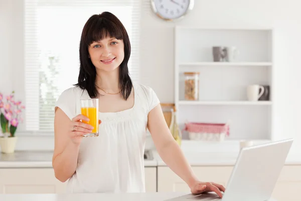 Vacker brunett kvinna med ett glas apelsinjuice medan re — Stockfoto