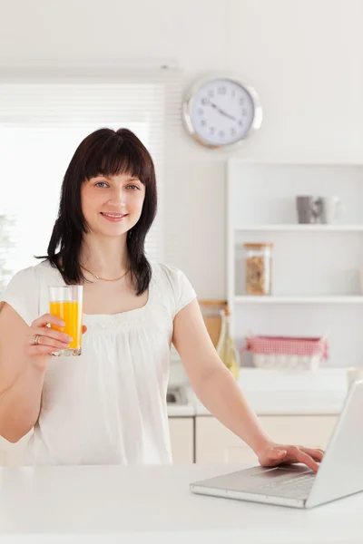 Ładny brunetka dama trzyma kieliszek soku pomarańczowego, natomiast piętro — Zdjęcie stockowe