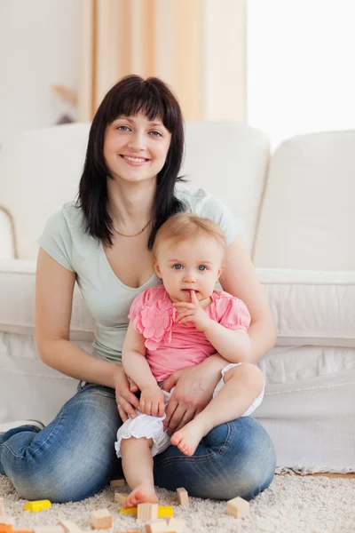 Schöne Frau hält ihr Baby auf dem Arm, während sie auf einem — Stockfoto