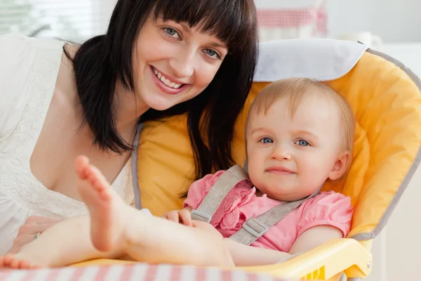 格好良いブルネット女性が座っている間彼女の赤ん坊を持つポーズ — ストック写真