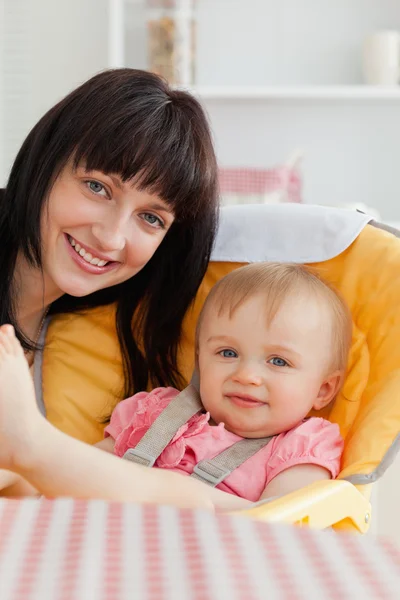 Oturma sırasında bebeği ile poz çekici esmer kadın — Stok fotoğraf