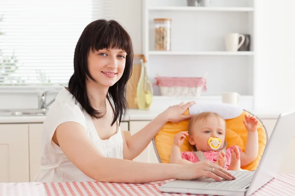 Schöne brünette Frau entspannt mit ihrem Laptop neben ihrem ba — Stockfoto