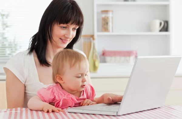 Belle femme brune montrant son ordinateur portable à son bébé tout — Photo
