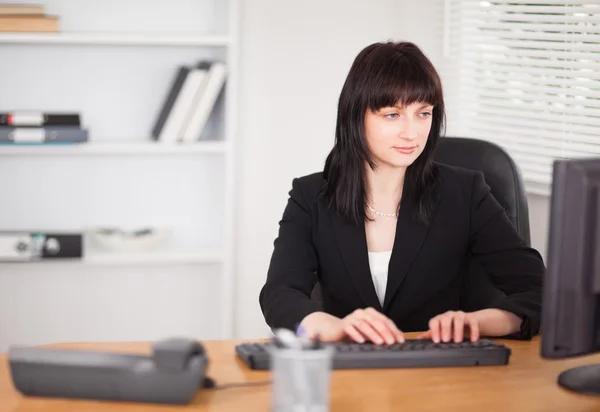 Όμορφη μελαχρινή γυναίκα που εργάζεται σε έναν υπολογιστή, ενώ κάθεται στο — Φωτογραφία Αρχείου