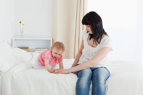 Beautiful brunette woman enjoying a moment with her baby while s — Stock Photo, Image