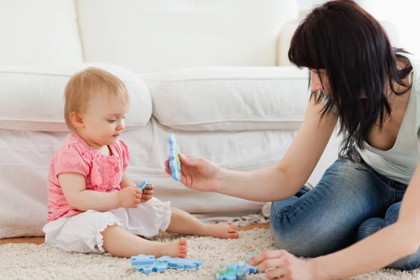 stock image Beautiful woman and her baby playing with puzzle pieces while si