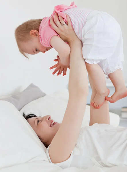 Vacker brunett kvinna leker med hennes barn liggande på en b — Stockfoto