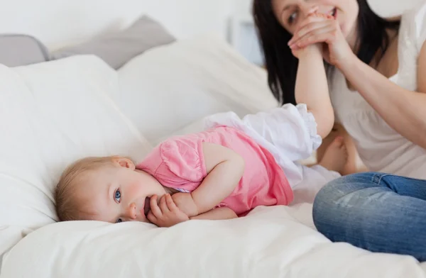 Snygg brunett kvinna leker med hennes barn medan liggande o — Stockfoto