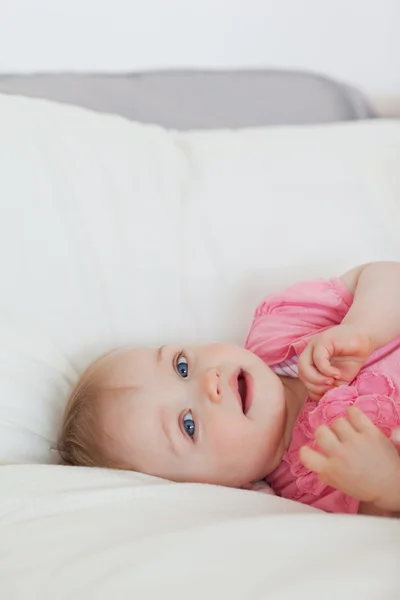 Lovely blond baby lying on a bed — Stock Photo, Image