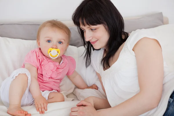 Attractive brunette female looking at her baby while lying on a — Stock Photo, Image