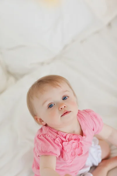 Roztomilé dítě, zatímco sedí na posteli při pohledu na fotoaparát — Stock fotografie