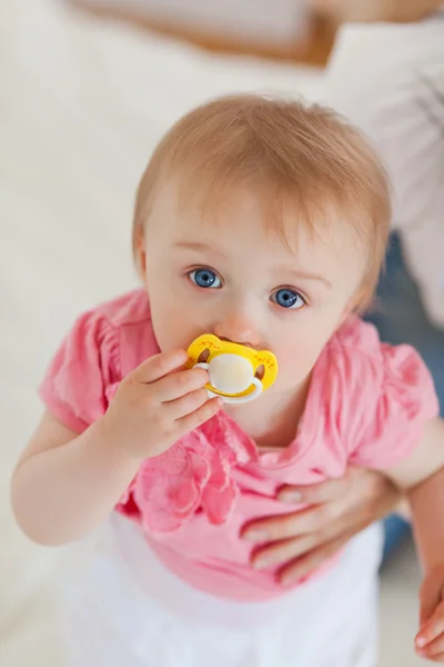 Bébé mignon regardant la caméra alors qu'elle est tenue par sa mère sur un be — Photo