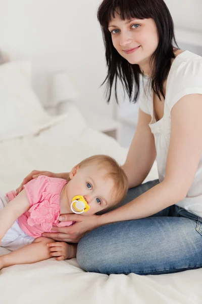 Attraktive brünette Frau posiert mit ihrem Baby, das auf ihr liegt — Stockfoto