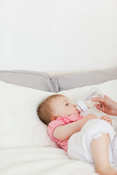 Vrouwelijke hand flesvoeding haar baby op een bed — Stockfoto
