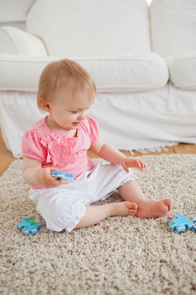 Puzzle parçaları ile halı üzerinde otururken oynayan bebek — Stok fotoğraf