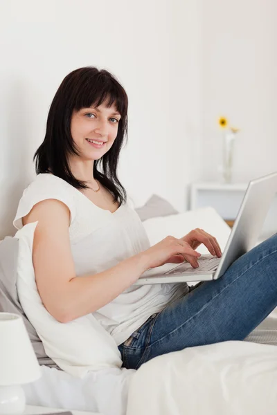 Attraktive brünette Frau entspannt mit ihrem Laptop im Sitzen — Stockfoto