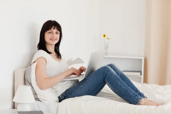 Güzel esmer kadın otururken onu laptop ile rahatlatıcı — Stok fotoğraf
