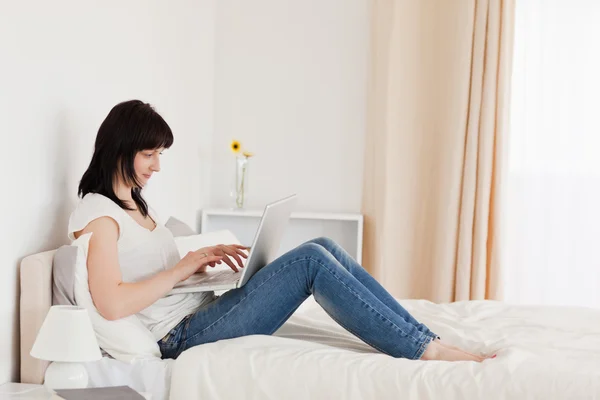 Belle femme brune se détendre avec son ordinateur portable tout en sitti — Photo