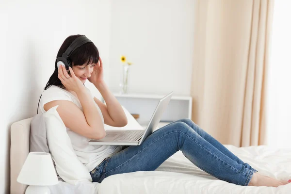 Affascinante donna bruna rilassante con il suo computer portatile mentre seduto o — Foto Stock