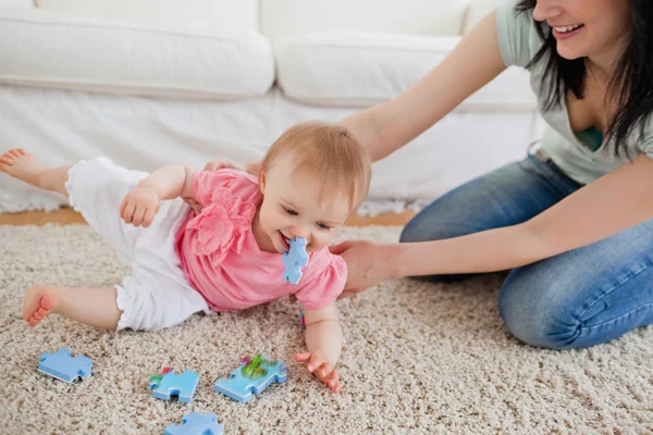 Bella donna e il suo bambino giocare con pezzi di puzzle mentre sitti — Foto Stock