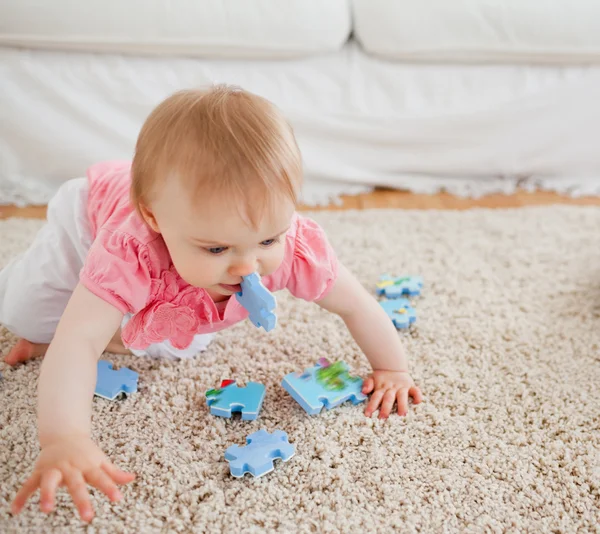 Прекрасна блондинка грає з шматочками головоломки на килимі — стокове фото