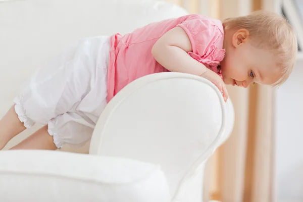 Schattige blonde baby permanent op een sofa — Stockfoto